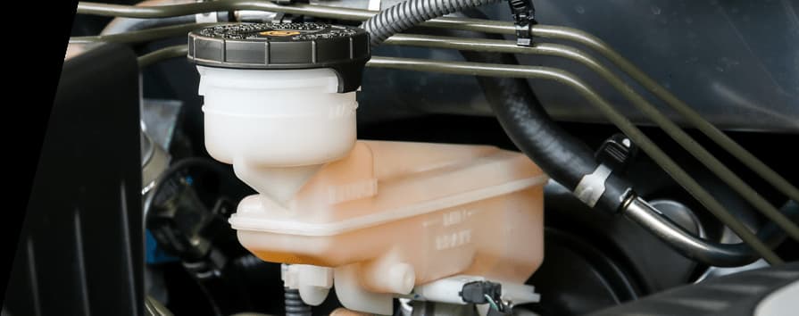 Gruppo pompa freno e serbatoio del liquido con tubi idraulici per il funzionamento dell'impianto frenante Pompa freno con serbatoio del liquido traslucido e tubi freno che mostrano i componenti dell'impianto frenante idraulico