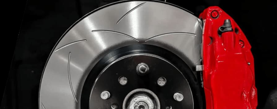 Disco scanalato e pinza DBA in evidenza nella pagina del catalogo dischi e tamburi 2020 Disco freno scanalato DBA con pinza rossa mostrato in un primo piano dell'installazione ad alte prestazioni