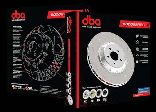 Dischi freno in due pezzi DBA Serie 5000 con struttura ad alto contenuto di carbonio e tecnologia avanzata di gestione termica Confezione del disco freno in due pezzi DBA Serie 5000 con scatola del prodotto recante lo schema tecnico e il disco ad alte prestazioni con campana in alluminio