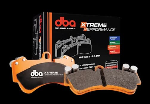 Pastiglie freno DBA Xtreme Performance progettate per uso in pista, traino con elevata massa complessiva e applicazioni fuoristrada gravose Pastiglie freno DBA Xtreme Performance con piattelli metallici arancioni e materiale d'attrito mostrate accanto alla confezione di vendita