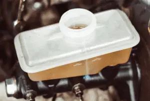 Serbatoio del liquido freni riempito correttamente che mostra il livello di liquido alla tacca di massimo a seguito dello spurgo completo dell'impianto frenante Serbatoio del liquido freni in plastica traslucida che mostra il livello del liquido alla linea di riempimento massimo corretta dopo aver completato la procedura di spurgo
