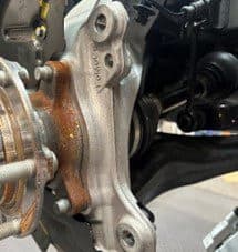 Passo 4A: Ispezione della fusione del mozzo OE per potenziali punti di contatto con la pinza DBA dopo la modifica del piatto porta-ceppi Primo piano della fusione del mozzo di primo equipaggiamento e del piatto porta-ceppi modificato che mostra i potenziali punti di contatto con la pinza DBA durante l'installazione