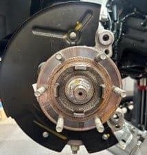 Passo 3B: Piatto porta-ceppi modificato rimontato sul veicolo per la prova di montaggio della pinza DBA a 6 pistoni dopo i tagli di gioco Piatto porta-ceppi modificato rimontato sul mozzo del veicolo con i tagli di gioco completati per il corretto montaggio dell'upgrade della pinza DBA a 6 pistoni